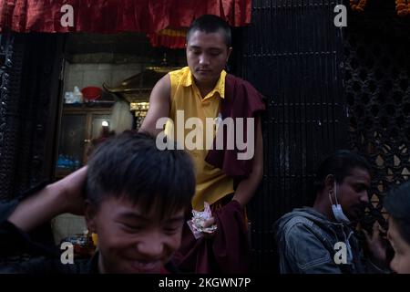 After taking a small sip of holy water offered by a monk, a young man wets the back of his head as a blessing. Boudhanath. Kathmandu. Nepal. Stock Photo