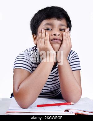 Child tired of school learning. Little boy unhappy face sitting at table .Preschooler education. Depressed kid portrait. Bored of studies pupil Stock Photo