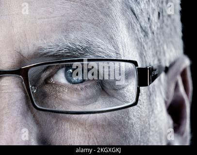 Eye Male half face glasses mature man age 50-55 years with designer glasses spectacles close up clear blue eye sight direct looking facing forward Stock Photo