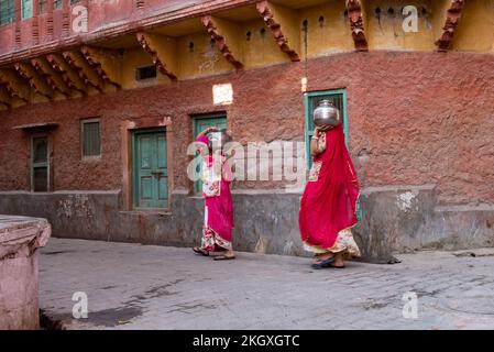 Indian Women Carrying Water Pots On Their Heads. Transferring water home Stock Photo