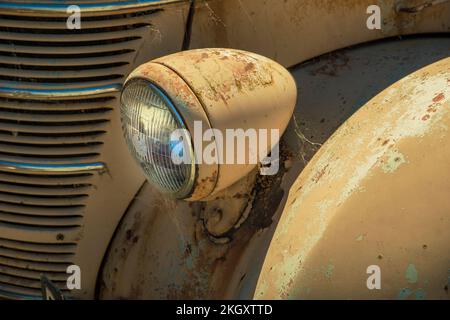 A rusty headlamp, front fender and grille of an old brown International truck Stock Photo