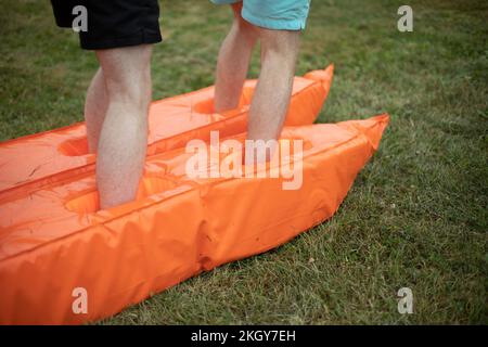 Men feet in shorts. Sports competition in stadium. Fun sport. Leg exercise. Orange inventory for games. Game for team. Stock Photo