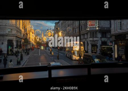 Seen from the top deck of a London bus are hanging Christmas-themed decorations which are suspended above the Strand in late afternoon autumn sunlight, on 22nd November 2022, in London, England. Stock Photo