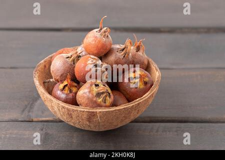 Bowl with common medlar fruit on wooden rustic table. Mespilus germanica Stock Photo
