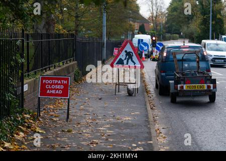 Road works, skid risk, re-surfacing, carriageway, stone chippings, grit, sweeper, roller, vehicle, skidding, red warning sign, footway works, footpath Stock Photo