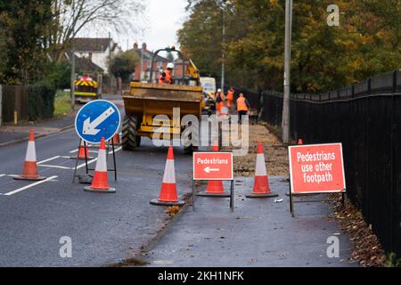 Road works, skid risk, re-surfacing, carriageway, stone chippings, grit, sweeper, roller, vehicle, skidding, red warning sign, footway works, footpath Stock Photo