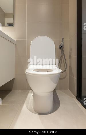 Front view of white toilet bowl with opened lid in a modern bathroom. Sanitary equipment for a home Stock Photo