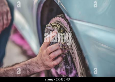 Auto detailing worker washing a customer car wheel Stock Photo
