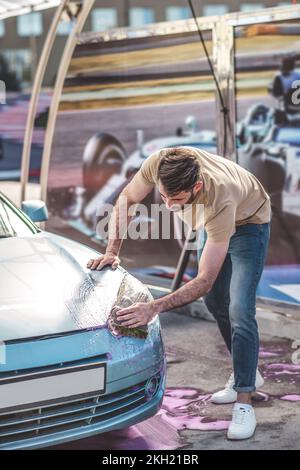 Service station worker cleaning the car headlight Stock Photo