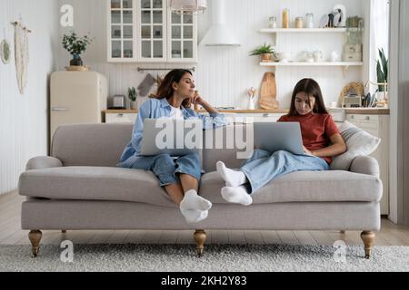 Family mother and daughter using laptops together while sitting on sofa in living room at home Stock Photo