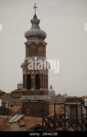 A vertical shot of the Campanile of the San Bartolomeo in Venice surrounded by red-tiled rooftops Stock Photo