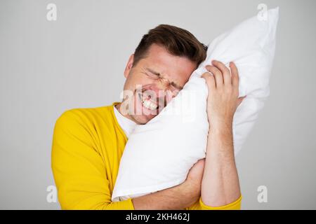 Portrait of Young Caucasian man in bed angry about noise  Stock Photo