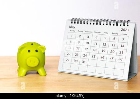 May 2023 calendar and piggy bank on a wooden table Stock Photo