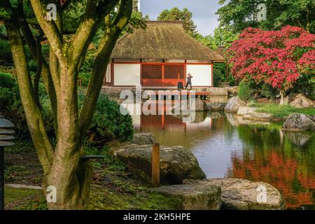 Autumn coming in japanese garden ( Botanical garden of Hamburg) - woman doing yoga exercises at early morning in botanical park of Hamburg  Planten un Stock Photo