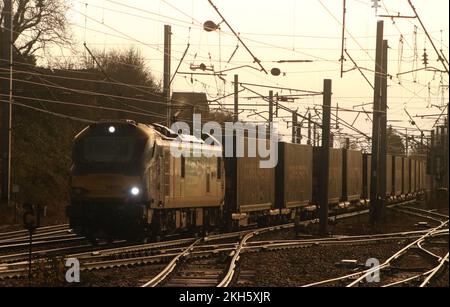 Sunlight reflecting off the side of a container train as it passes through Carnforth North Junction on West Coast Main line on 23rd November 2022. Stock Photo