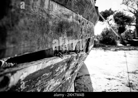 A grayscale shot of a wooden boat moored on the white beach in Zanzibar Stock Photo
