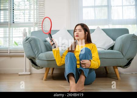 Woman killing mosquitoes hand holding fly swatter like weapon Stock Photo