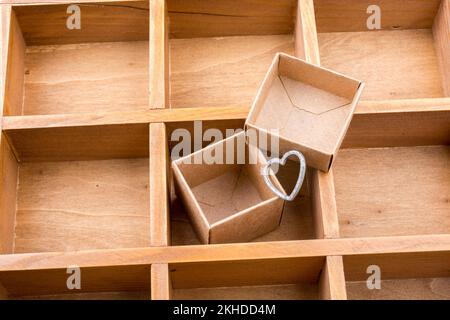 Open cardboard box inside a wooden box with compartments and a heart Stock Photo