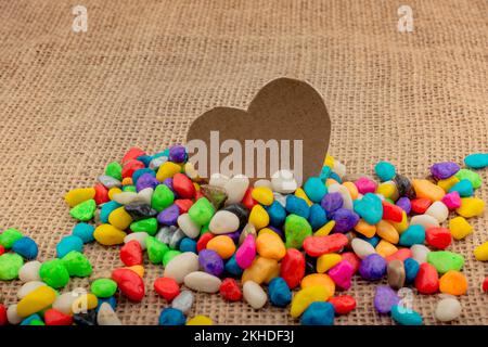 Paper heart amid colorful pebbles on canvas ground Stock Photo