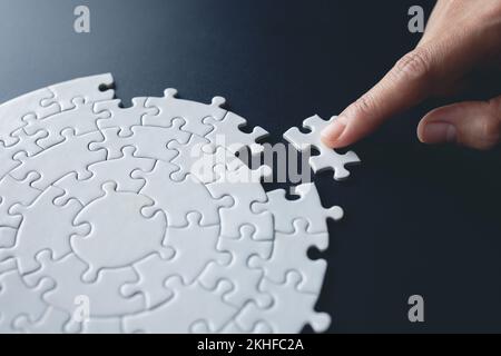 The correct solution. Teamwork, Solving and completing the task. Last piece of jigsaw puzzle. Assembling  jigsaw puzzle pieces. Stock Photo