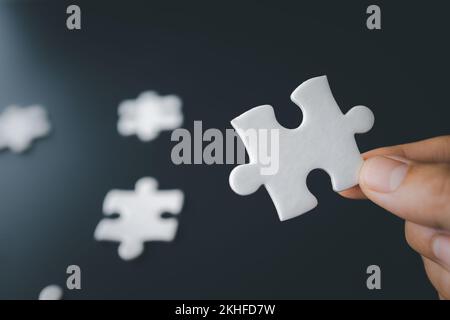 Hand holding jigsaw puzzles, Business partnership concept. hands of businessmen connect puzzle pieces on dark background. Business concept idea, teamw Stock Photo