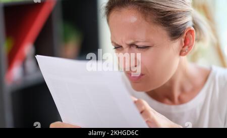 Concentrated female read papers, squinting to see more clearly Stock Photo