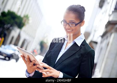 Free wifi - a perk of the city. A happy young businesswoman using her digital tablet in the city. Stock Photo