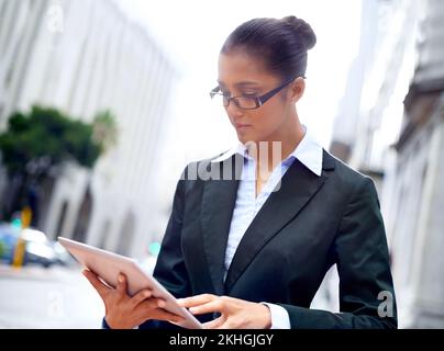 Doing business on the go. A young businesswoman using her digital tablet in the city. Stock Photo