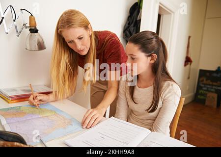 Been a while since she had to do this. a teenage girl getting some studying help from her mother. Stock Photo