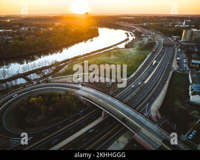 A drone view of a city skyline with highways and buildings near the river at sunrise in New Brunswick, Rutgers, Hub City, USA Stock Photo