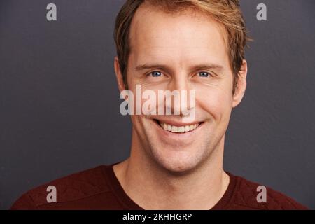 That smile gives him extra hunk points. Studio portrait of a handsome man in a sweater. Stock Photo