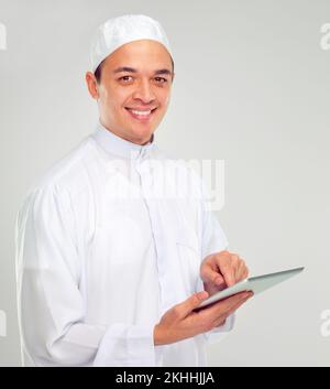 Digital life of the modern man. Studio portrait of a young muslim man using a digital tablet. Stock Photo