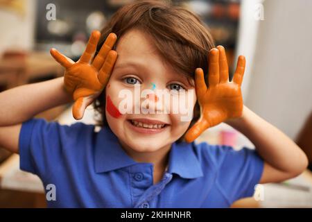 Becoming the art. Cute little boy showing you his paint covered hands. Stock Photo