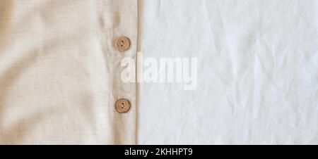 Crumpled off white natural linen organic eco textiles canvas background. Beige linen bed fabric with brown buttons. Top view Stock Photo