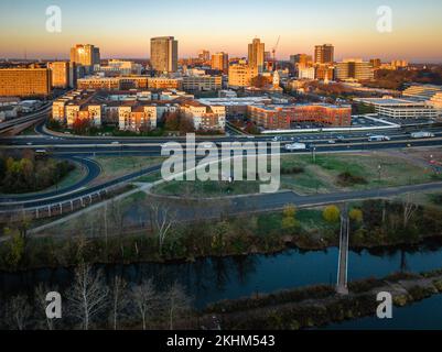 A drone view of a city skyline with buildings illuminated by sun rays near the river at sunrise in New Brunswick, Rutgers, Hub City, USA Stock Photo