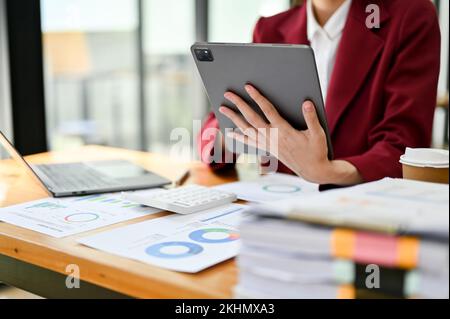 cropped image, Businesswoman using digital tablet, analyzing financial data and working on her financial data report. Stock Photo