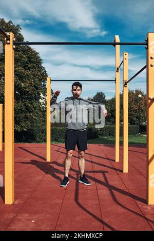 Young man stretching before his workout in a modern calisthenics street workout park. Man wearing sportswear Stock Photo