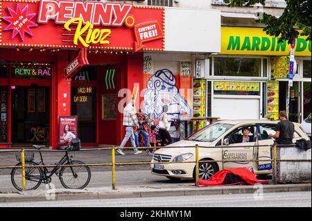 A woman cab driver waits for customers in front of the Penny Kiez supermarket on the Reeperbahn. Stock Photo