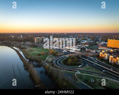 A drone view of a city skyline with buildings near the river at sunrise in New Brunswick, Rutgers, Hub City, USA Stock Photo