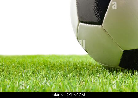 Macro of classic soccer ball on artificial grass and white isolated background. Horizontal composition. Stock Photo