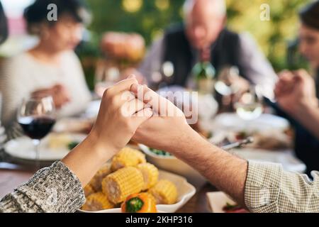 Party, food and family holding hands for prayer before eating chicken, barbecue or turkey at a social event. Corn, Christmas and Christian friends Stock Photo