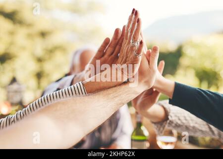 Support, high five and community with hands of family at dinner table for celebration, happy and lunch together. Collaboration, faith and festive with Stock Photo