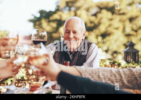 Wine, cheers and grandpa in christmas toast with family for holiday celebration together with food and friends in garden. Hands, wine glasses and Stock Photo