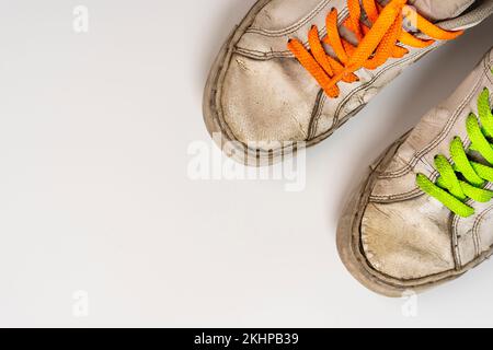 worn old torn white sneakers with colored laces on a white background Stock Photo