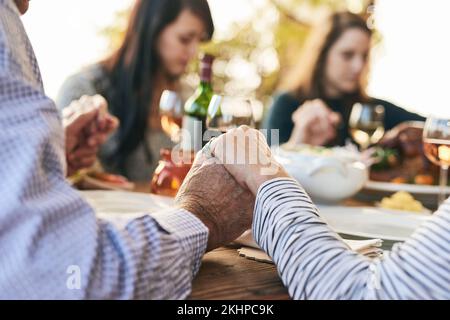 Family, prayer and lunch for thanksgiving, celebration or party in garden, backyard or outdoor restaurant. Holding hands, mindfulness and gratitude Stock Photo
