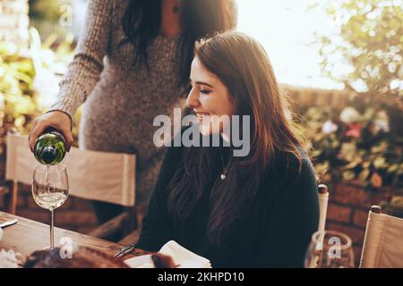 Dinner party, nature and pouring wine for woman sitting at table in restaurant for social event, party and celebration. Festive, alcohol and girl Stock Photo