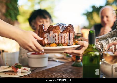 Thanksgiving, turkey and hands with a family eating a meal outdoor together in celebration of tradition. Christmas, chicken and party with a man and Stock Photo