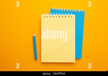 Yellow and blue notebook with pencils on a yellow background with a place for an inscription Stock Photo
