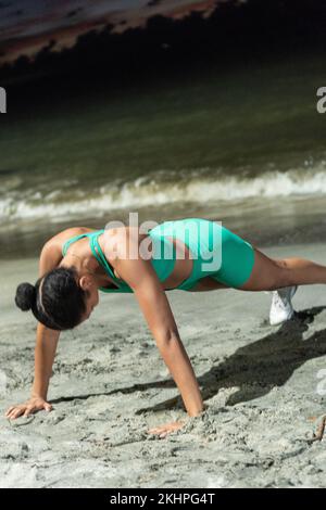 Young woman doing push-ups on the beach Stock Photo