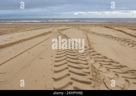 tyre tracks on a sandy beach leading to the sea Stock Photo